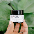 Annmarie Illuminating Pearl Mask brightening facial treatment held in hand against lush green foliage