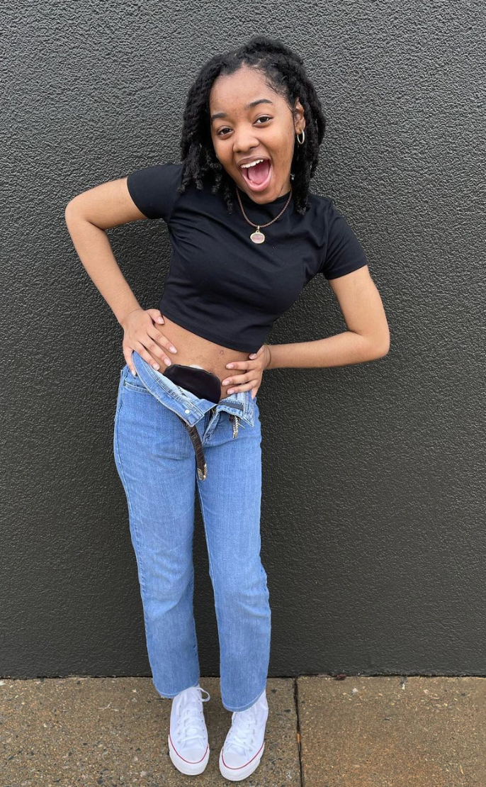 Woman standing against gray wall in black elastic ostomy bag cover