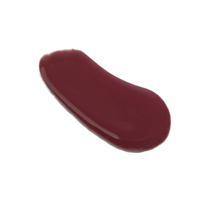 A single swipe of The Seaweed Bath Co Tinted Mineral Lip Shine SPF 20 in a glossy, deep burgundy shade—infused with nourishing shea butter—is spread smoothly on a white background.